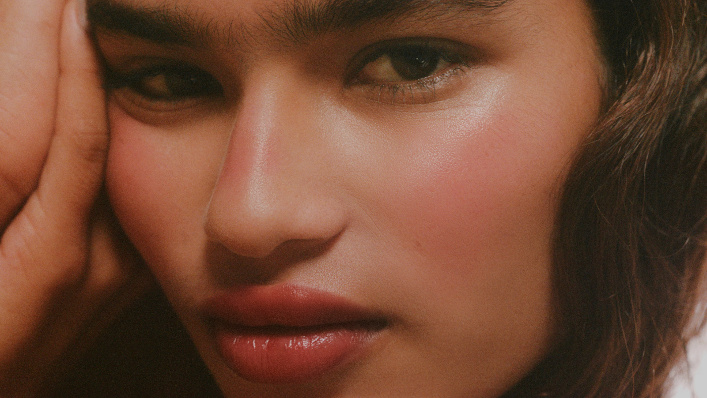 Close-up of a person with a hand on their face, with a warm color tone.